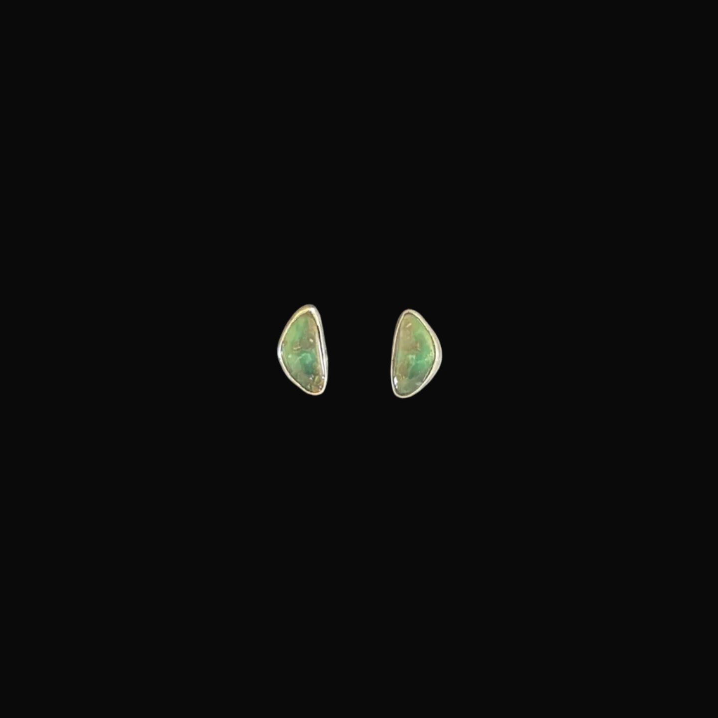 Pair of green turquoise earrings on a black textured background