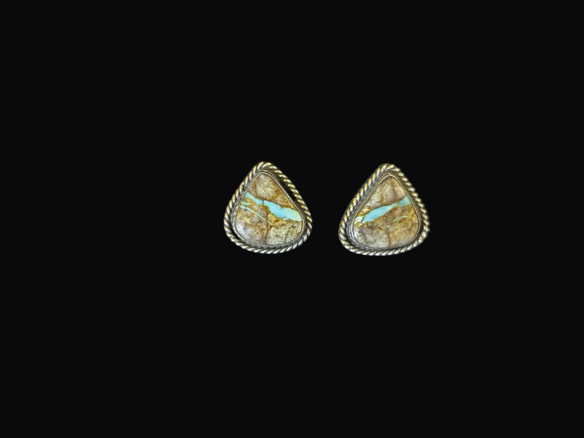 Pair of earrings with turquoise stones on a dark surface