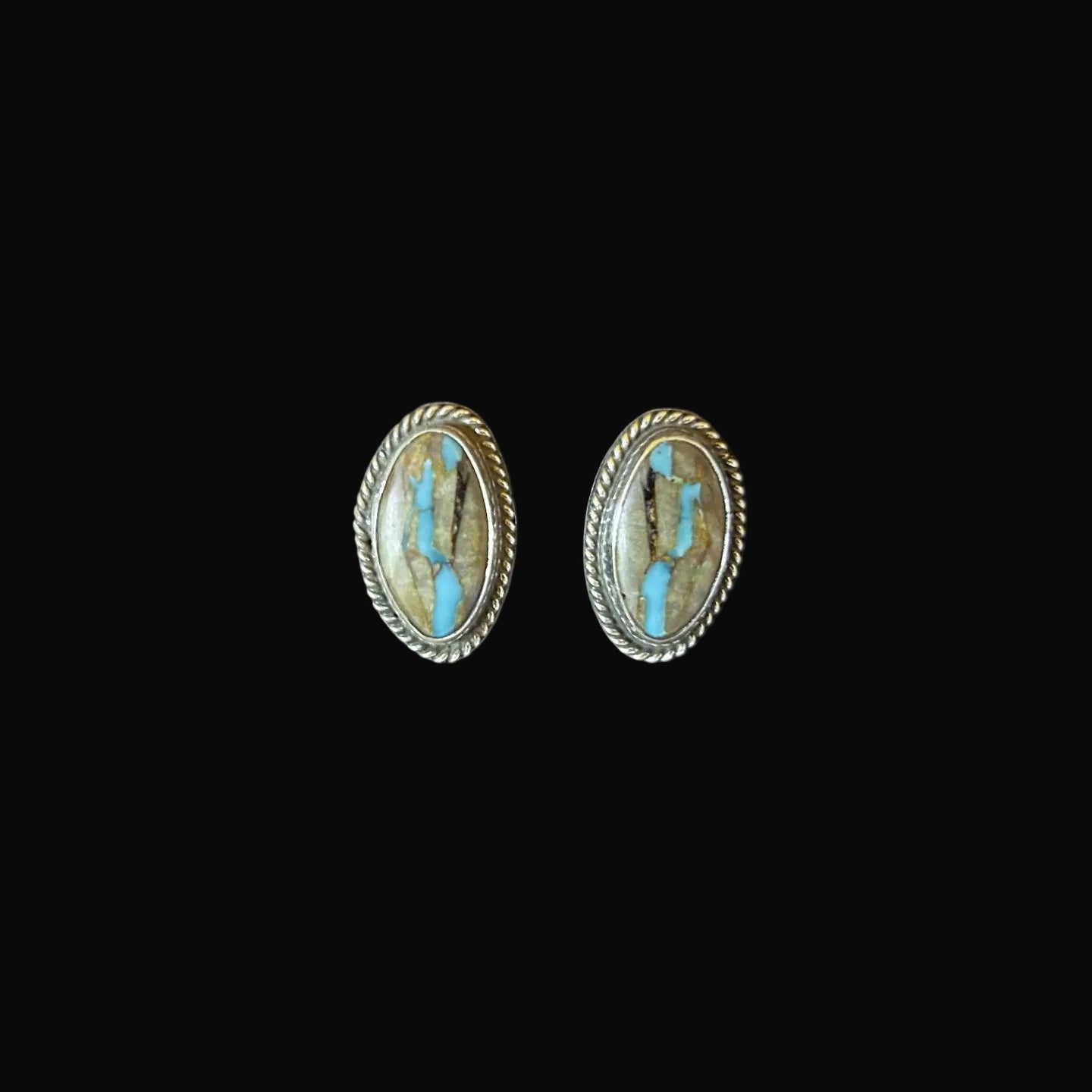 Pair of oval-shaped earrings with turquoise stones on a black background