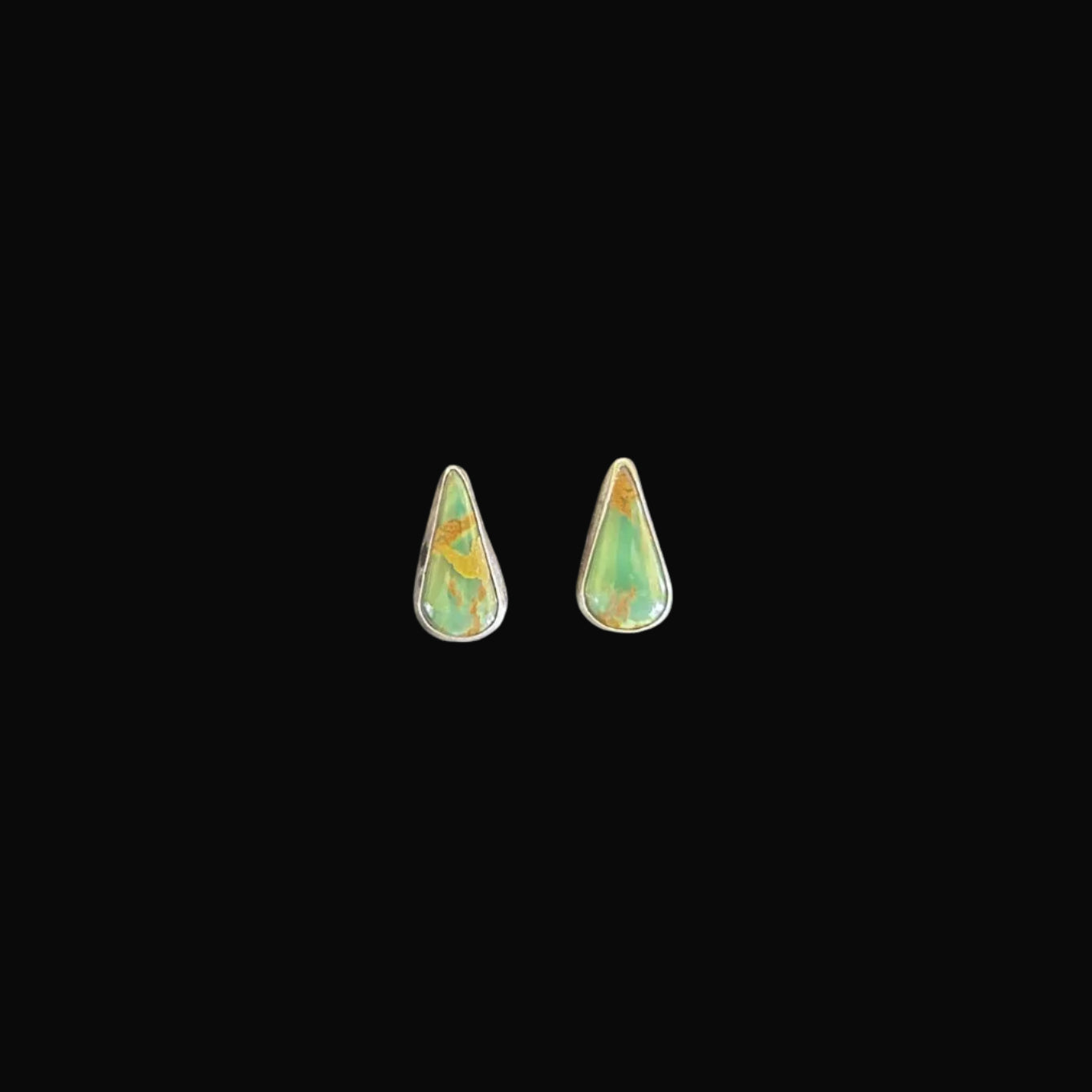 Two green teardrop-shaped stones on a black surface
